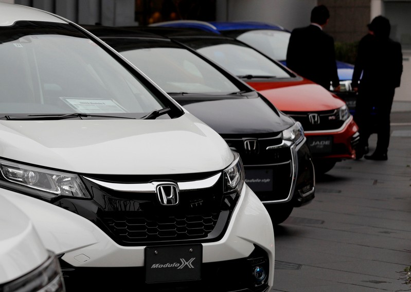 People chat in front of cars in a showroom at Honda's headquarters in Tokyo