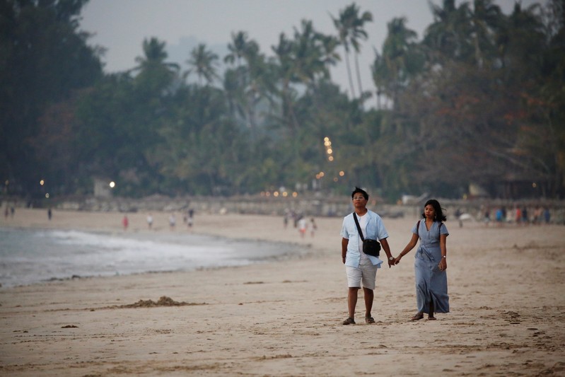Visitors walk on Ngapali beach in Thandwe,