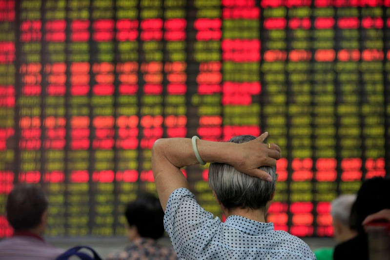 FILE PHOTO: Investors look at an electronic board showing stock information at a brokerage