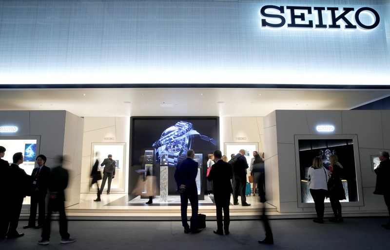 People walk past the exhibition stand of manufacturer Seiko at the Baselworld watch and