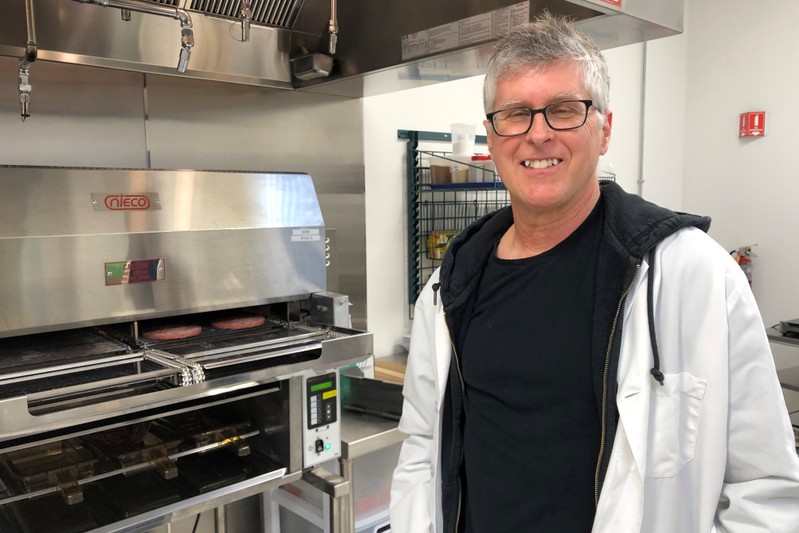 Impossible Foods Chief Executive Pat Brown poses in front of a flame broiler cooking its