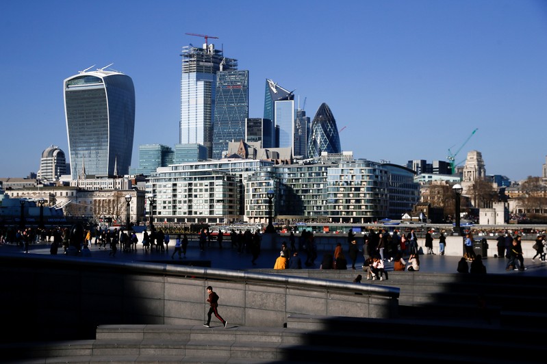 FILE PHOTO: The financial district can be seen as a person runs in the sunshine on London's