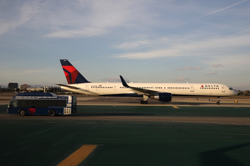 A Delta plane passes a Delta bus on the tarmac at LAX airport in Los Angeles