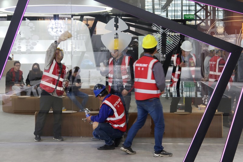 Workers set up the display stand for Chinese EV startup Singulato Motors in preparation for the