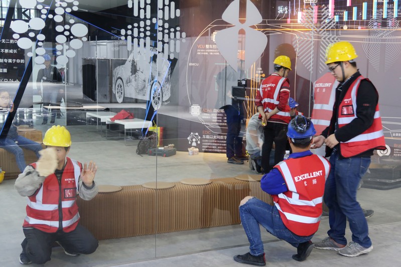 Workers set up the display stand for Chinese EV startup Singulato Motors in preparation for the