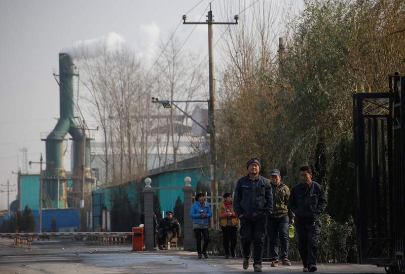 Smoke billows from a chimney as workers leave a factory in rural Gaoyi county near Shijiazhuang