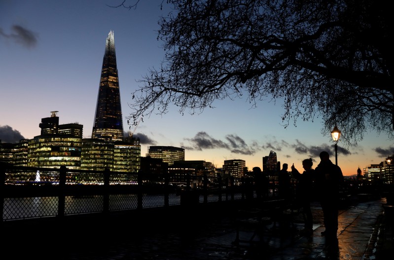 FILE PHOTO: People walk alongside the Thames as the sun sets behind The Shard in London