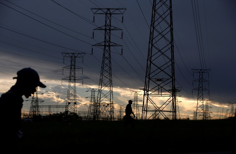 FILE PHOTO: Men walk past electricity pylons as they return from work in Orlando