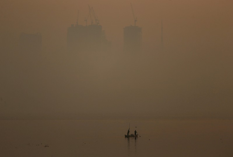 FILE PHOTO: Men row a boat in the waters of the Arabian Sea on a smoggy evening in Mumbai