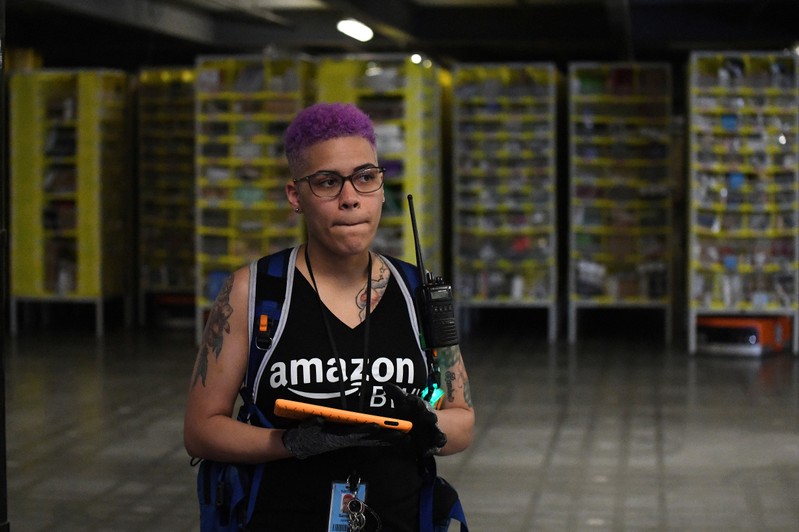 FILE PHOTO: Amazon worker Johnson walks through the robotic moving shelves with a protective