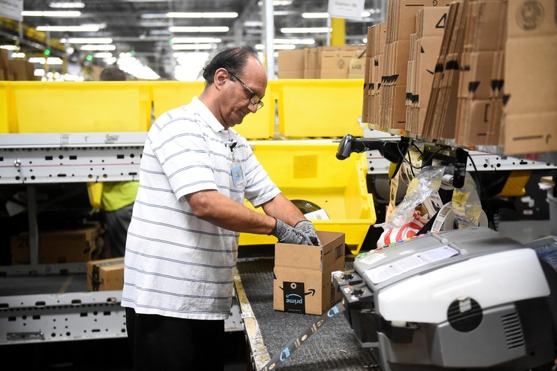 FILE PHOTO: Packing worker Zubair fills a delivery box with products at the Amazon fulfillment