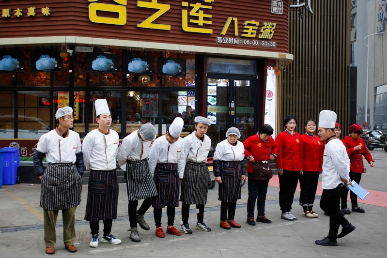 A chef talks to his kitchen staff during their morning assembly outside a restaurant in