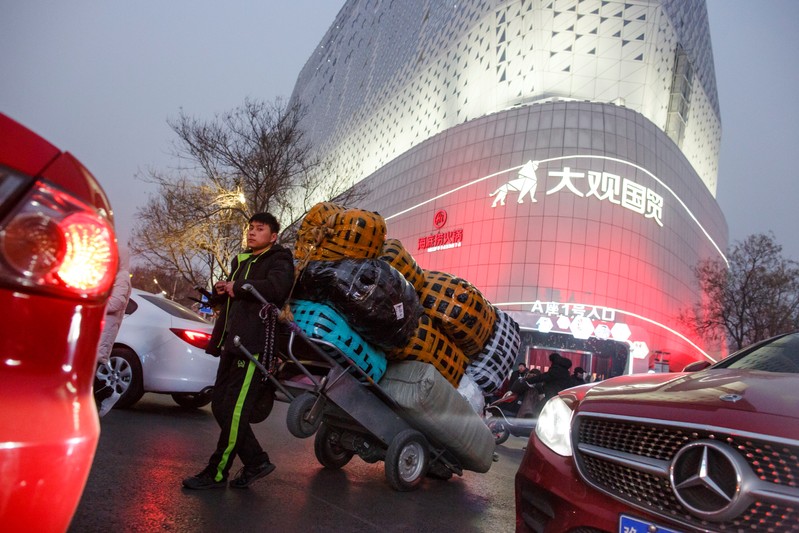 A deliveryman leans against a cart outside a wholesale market in central Zhengzhou