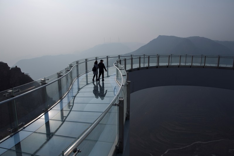 People walk on a horseshoe-shaped glass bridge over Fuxi Mountain valley outside Xinmi city