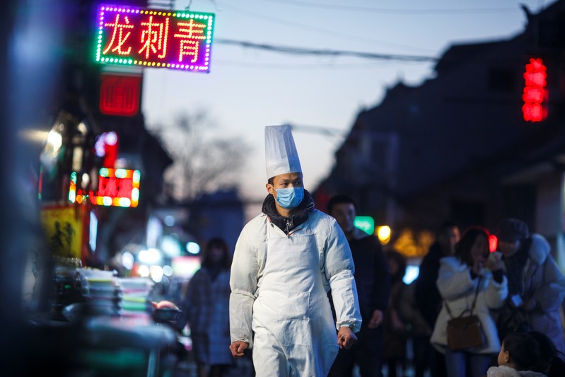 A chef walks outside a restaurant at night in the old town of Luoyang