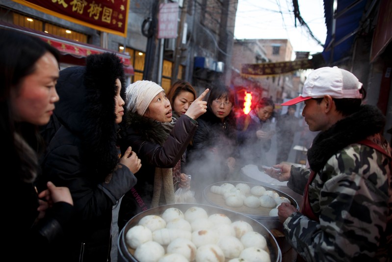 Women buy steamed buns from a street vendor in the old town of Luoyang