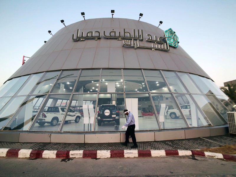 A worker cleans the front face of the car showroom of Abdul Latif Jamil Automobile, Saudi