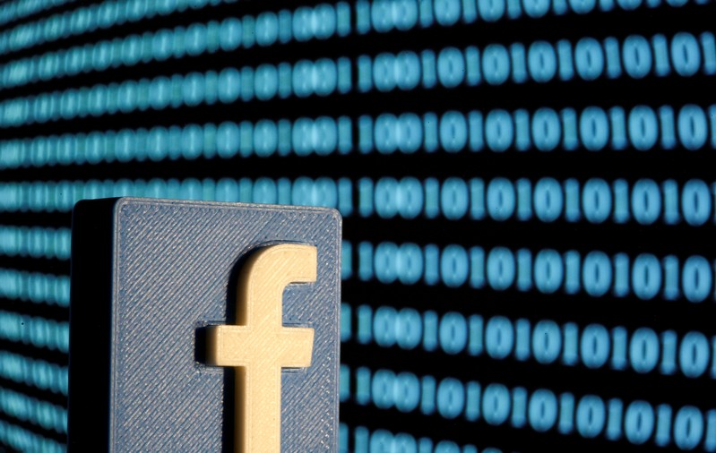 A 3-D printed Facebook logo is seen in front of displayed binary code in this illustration