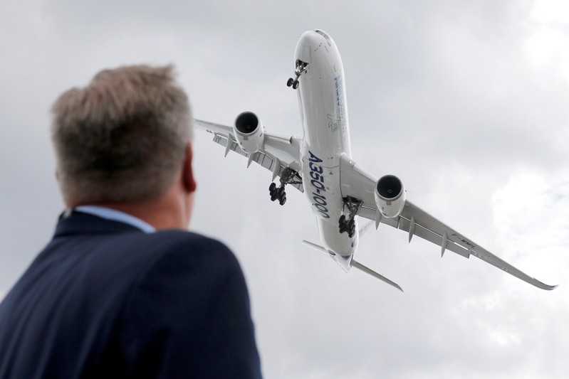 A visitor looks at an Airbus A350-1000 as he performs during the 53rd International Paris Air