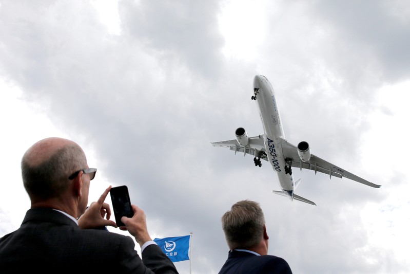 A visitor takes a picture of an Airbus A350-1000 as it performs during the 53rd International