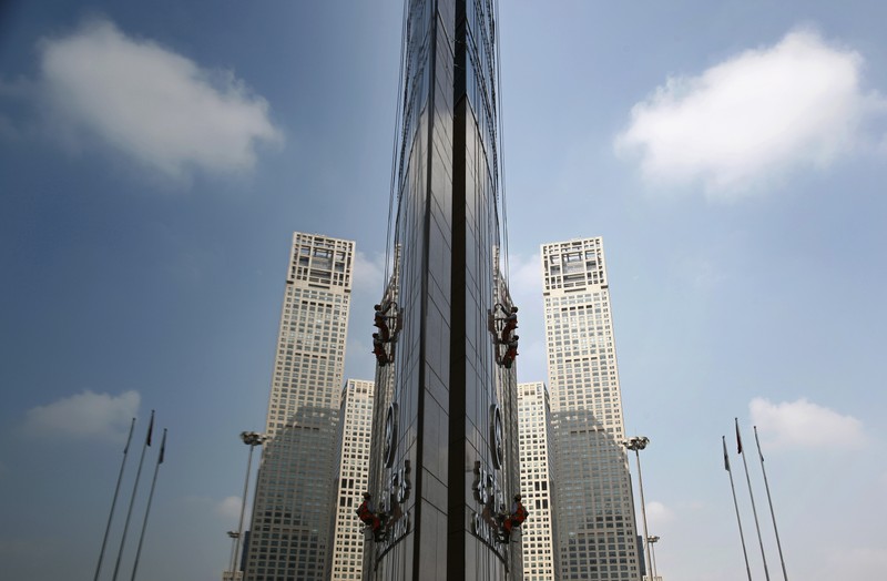 Workers are reflected on the glass window of the China Merchants Bank Building as they clean it