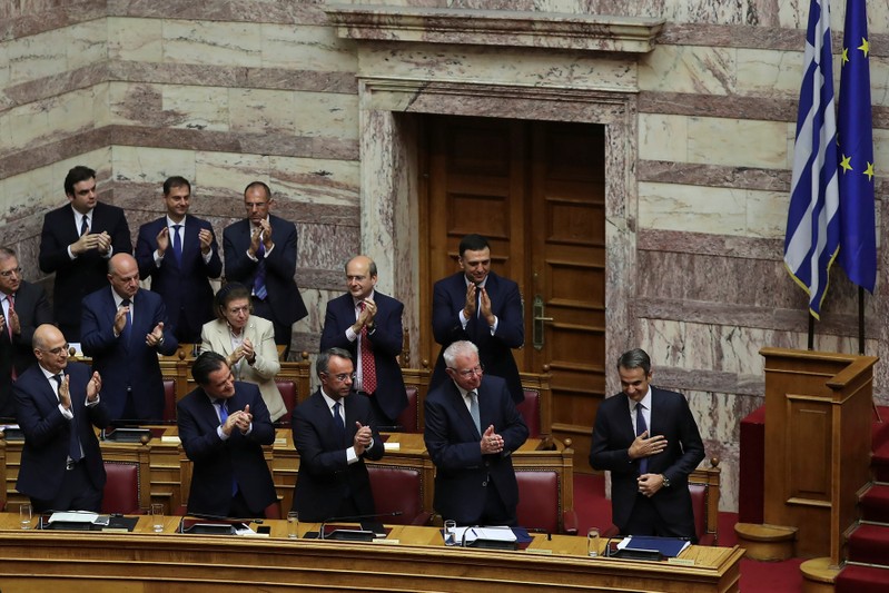 Greek PM Mitsotakis is applauded by his lawmakers and ministers after presenting his