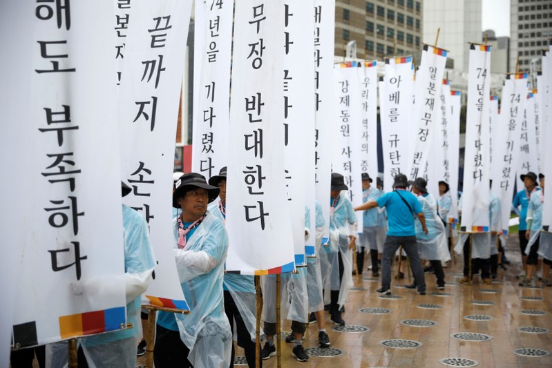 People hold banners denoucning Japanese Prime Minister Abe and his economic sanction during an
