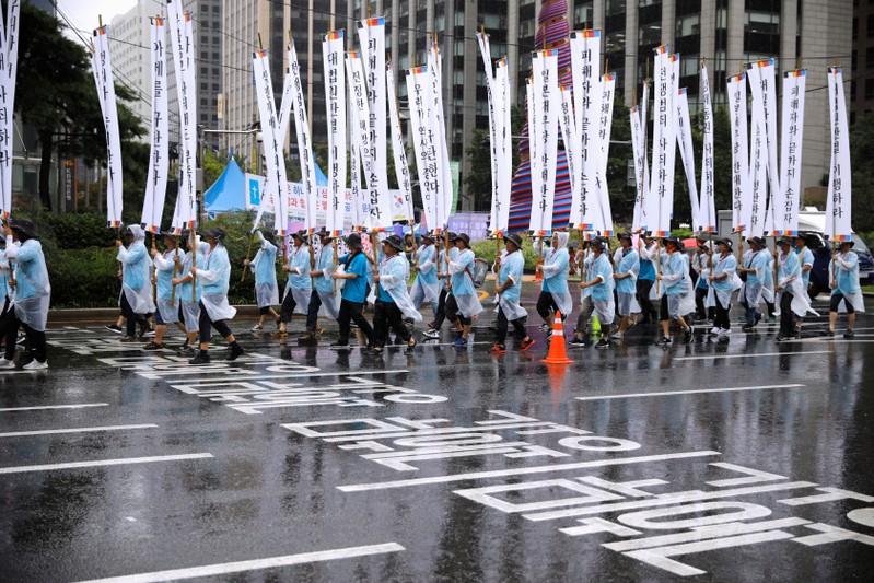 People march holding banners denouncing Japanese Prime Minister Shinzo Abe and his economic