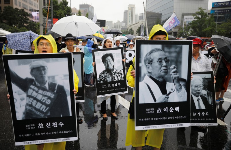 People march holding portraits of deceased victims of wartime forced labor during the Japanese