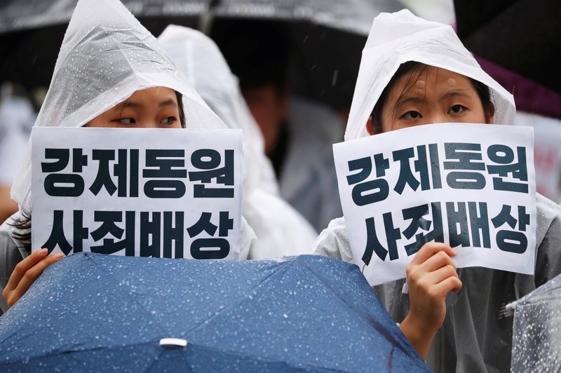 Women hold signs that read 