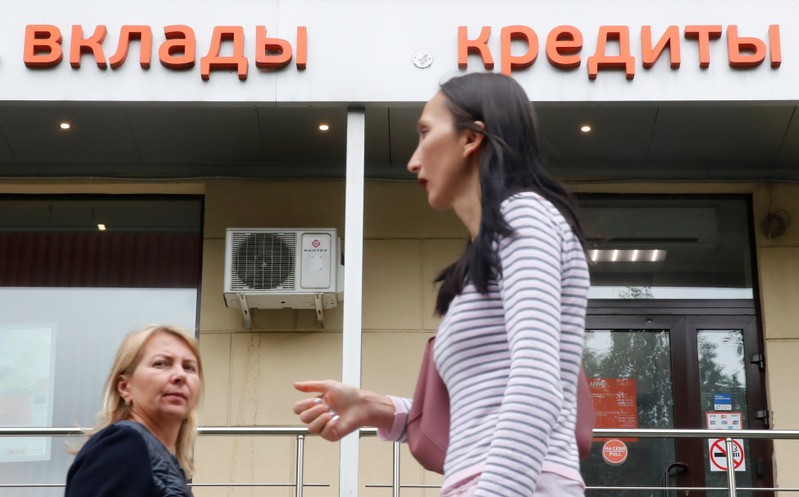 People walk past an office of a local bank in Moscow