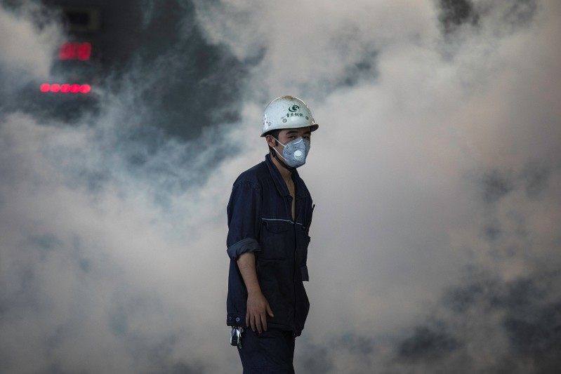 Worker stands near smoke from blast furnace at the Chongqing Iron and Steel plant in Changshou