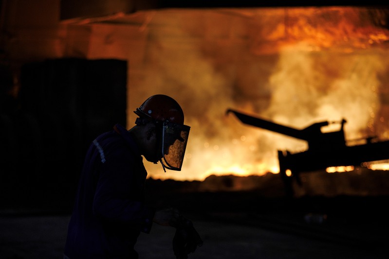 Worker is silhouetted against a blast furnace at the Chongqing Iron and Steel plant in