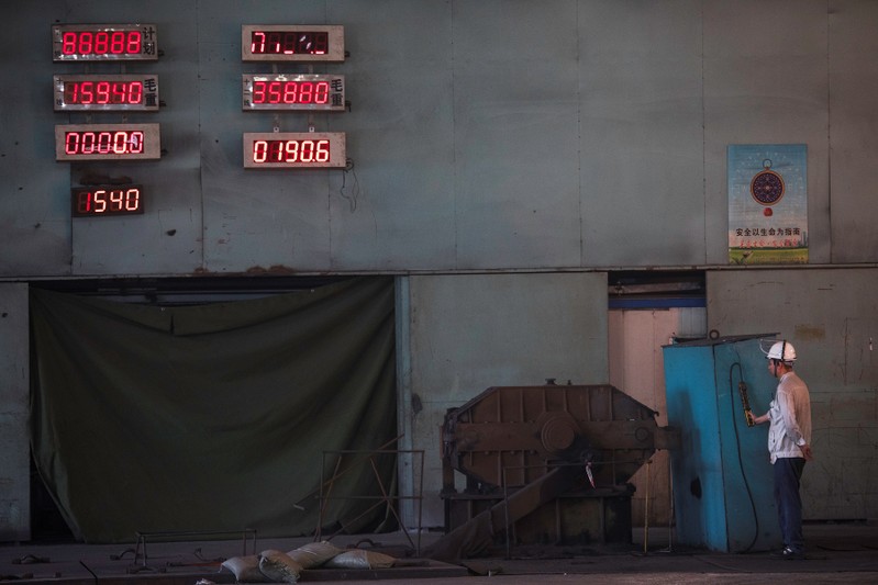 Worker is seen under electronic displays at the Chongqing Iron and Steel plant in Changshou