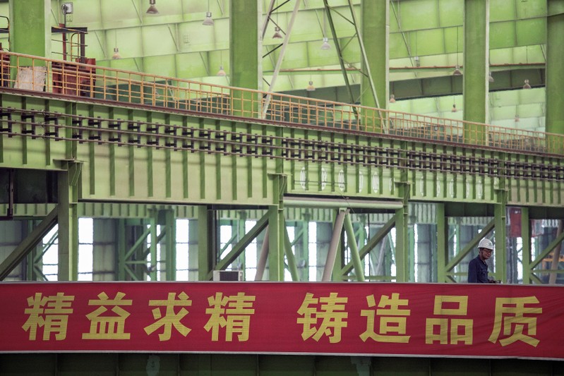 Worker walks by a banner at the Chongqing Iron and Steel plant in Changshou
