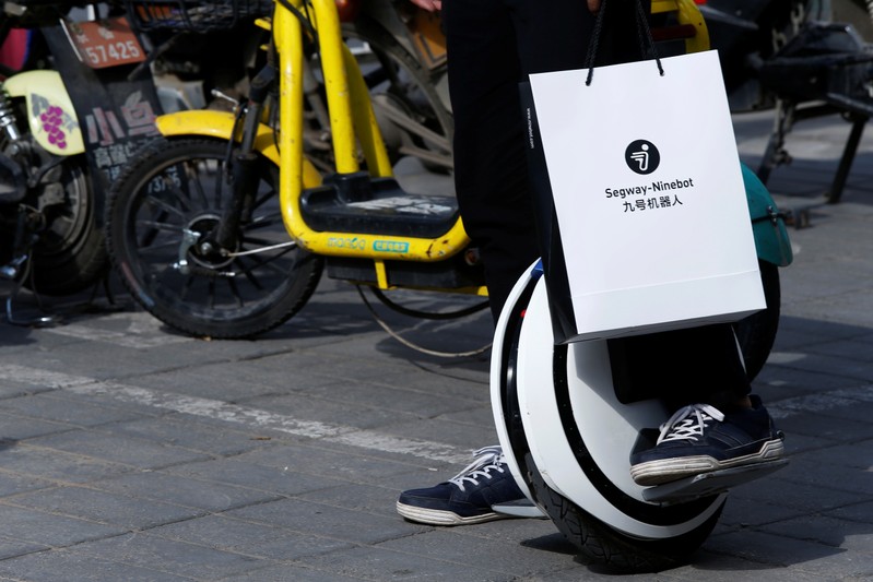 Man rides a Ninebot One electric unicycle near the venue of a Segway-Ninebot product launch