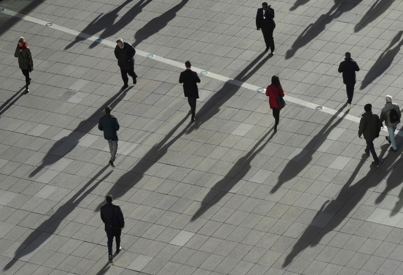 FILE PHOTO: People cast long shadows in the winter sunlight as they walk across a plaza in the