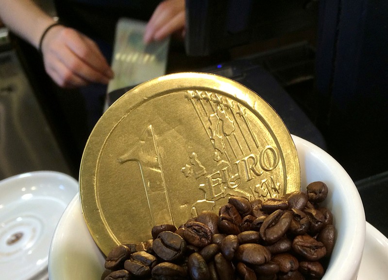 An employee uses a cash till behind a chocolate shaped one Euro coin at a cafe in central