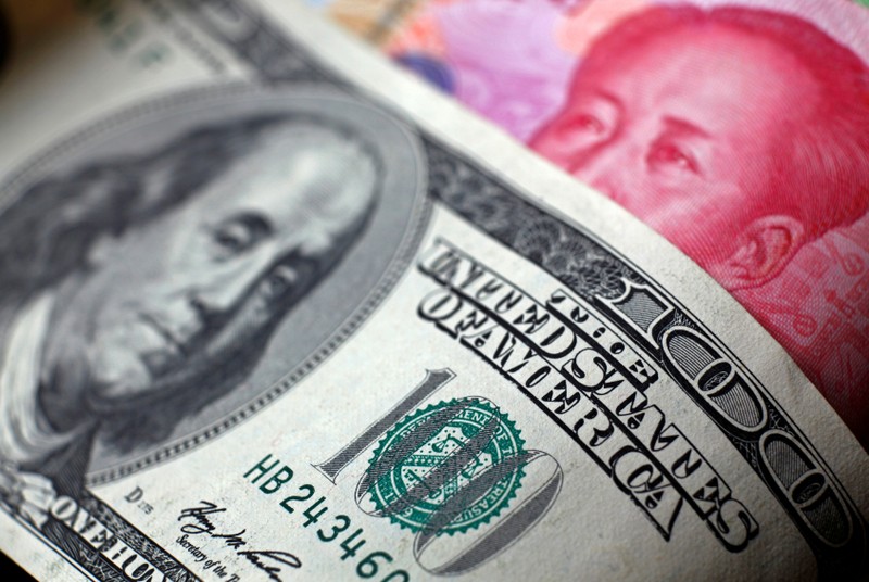 FILE PHOTO: File photo of a Chinese 100 yuan banknote being placed under a $100 banknote in