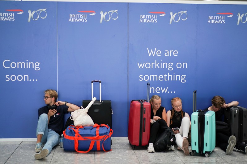 People wait inside Terminal 5 at Heathrow Airport as IT problems caused delays in London