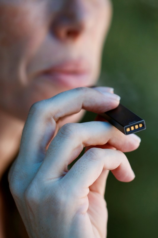 FILE PHOTO: A woman smokes a Juul e-cigarette in this posed picture, near Jerusalem
