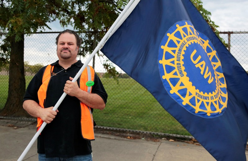 United Auto Worker, Aramark worker Mike Mucci, carries a UAW flag while picketing outside the