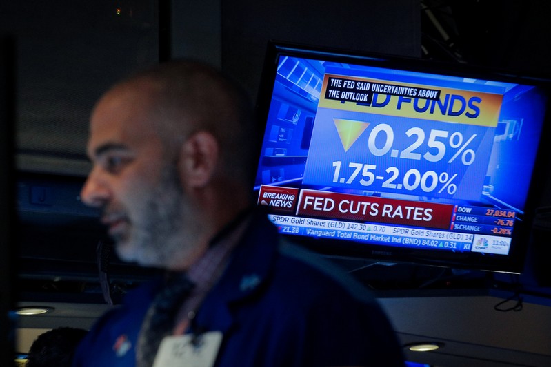 A screen displays the U.S. Federal Reserve interest rates announcement as traders work on the