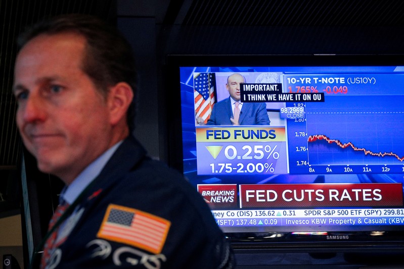 A screen displays the U.S. Federal Reserve interest rates announcement as traders work on the