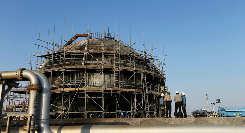 Workers are seen at the damaged site of Saudi Aramco oil facility in Abqaiq