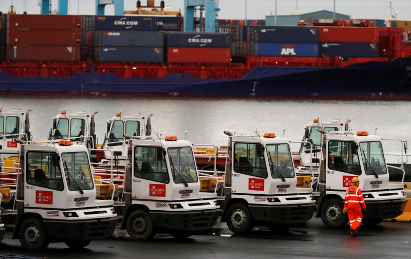 FILE PHOTO: A dock worker walks in front of a container ship at Peel Ports Liverpool container