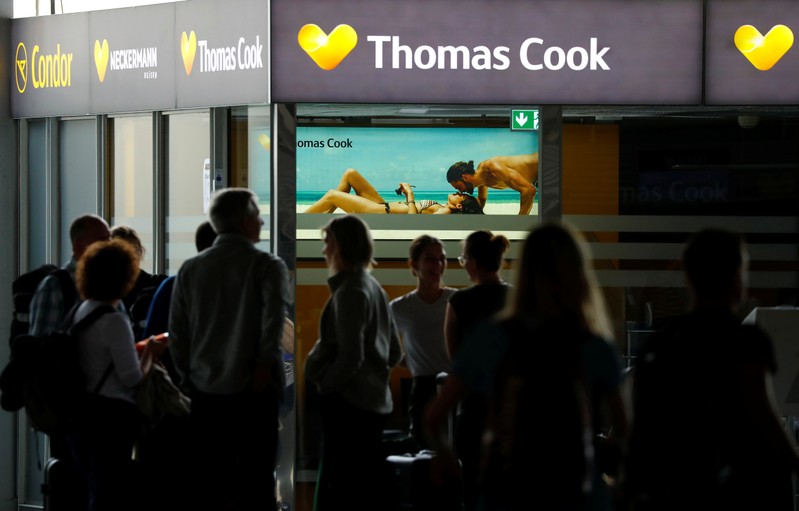 Passengers are silhouetted in front of a closed service counter of travel agent Thomas Cook and
