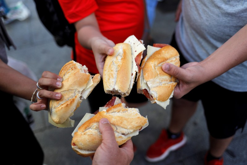 FILE PHOTO: Tourists show sadwhiches with ham and cheese bought in a bar in Madrid