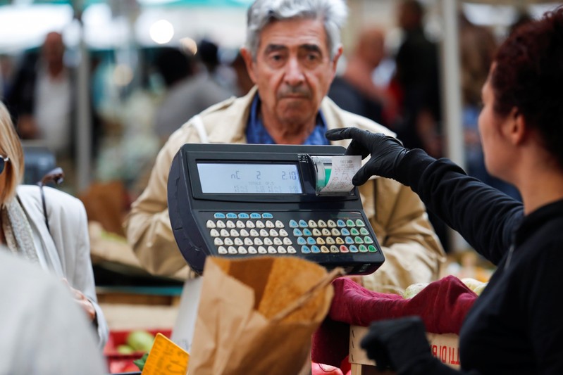 A man pays for items at the market in downtown Rome as Italy's cabinet prepares to approve a
