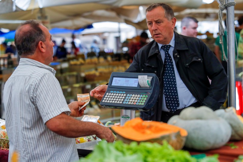 People pay for items at the market in downtown Rome as Italy's cabinet prepares to approve a
